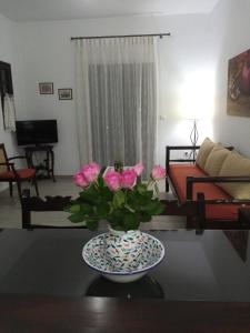 un vase avec des fleurs roses sur une table dans le salon dans l'établissement Vangelis Villas, à Agios Nikolaos