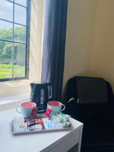 - un plateau avec deux tasses sur une table à côté d'une fenêtre dans l'établissement Mirfield Monastery B&B, à Mirfield