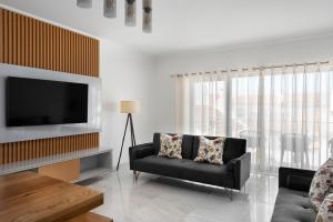 a living room with a couch and a television at Lazy Days - Adults Only - Duna Parque Resorts & Hotels in Vila Nova de Milfontes