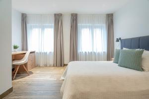 een slaapkamer met een bed, een bureau en ramen bij Ronces Hostel in Pamplona
