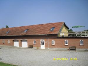 a large brick building with benches in front of it at Hellesvang in Guderup