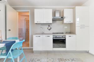 a kitchen with white cabinets and a table and chairs at Villa Fantagali apt 501 in Marina di Campo