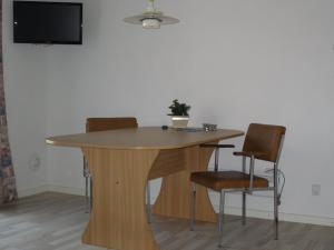 une table en bois avec des chaises et une télévision murale. dans l'établissement Hellesvang, à Guderup