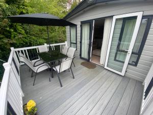 a deck with a table and chairs and an umbrella at Starling Six Berth caravan in Alford