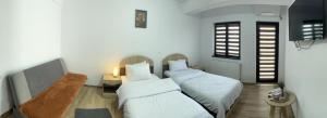 a bedroom with two beds and a table and a window at PENSIUNEA CAMELIA in Baia