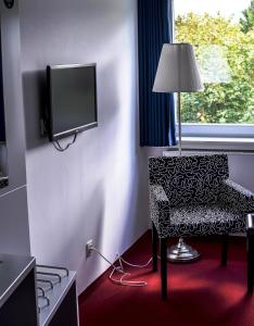 a hotel room with a chair and a tv at Hotel & Tagungszentrum Hessenkopf in Goslar