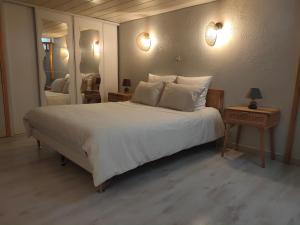 een slaapkamer met een groot wit bed en 2 spiegels bij Gite la Denteliere in Calais