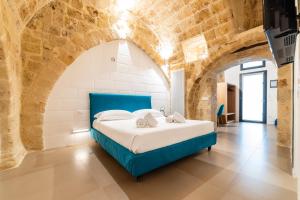 a bedroom with a blue bed in a brick wall at B&B A C-Caste in Monopoli