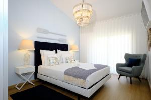 a bedroom with a bed and a chair and a chandelier at Resort Holidays Nazaré in Nazaré