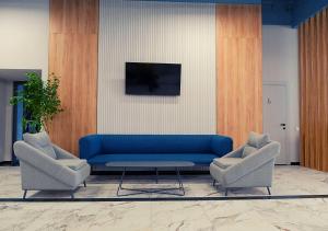 a living room with a blue couch and two chairs at ADD Hotel Almaty in Almaty