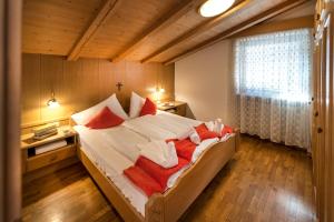ein Schlafzimmer mit einem großen Bett mit roten und weißen Kissen in der Unterkunft Art Residence Josefshof in Algund