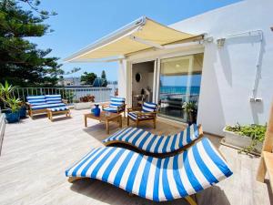 eine Terrasse mit blauen und weißen Stühlen und einem Sonnenschirm in der Unterkunft Il Profumo del Mare in Cagliari