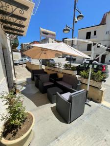 d'une terrasse avec des tables, des chaises et un parasol. dans l'établissement Le Suite Di Via Veneto, à Favara