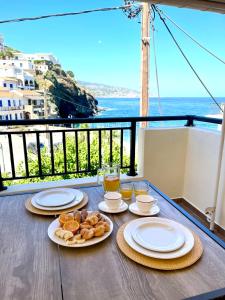 - une table avec des assiettes de nourriture et une vue sur l'océan dans l'établissement Seagulls' House, à Évdhilos