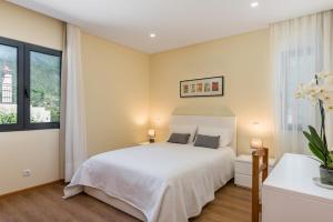 a bedroom with a white bed and two windows at Villa Teresa by Atlantic Holiday in São Vicente