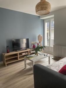 ein Wohnzimmer mit einem TV und einem Tisch in der Unterkunft Bel appartement T3 rénové avec cour intérieure - Villa Marie in Luchon