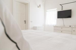 a white bedroom with a bed and a tv at Dimora Graziana 1909 in Locorotondo