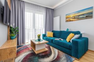un soggiorno con divano blu e tavolo di Baltini Premium Apartament Baltic Marina Residence a Kołobrzeg