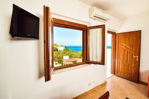 a room with a tv and a window with the ocean at SOLEMAREPONZA Casa il Bacio del Sole in Ponza