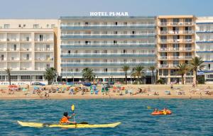 a man in a kayak in the water in front of a beach at Hotel Pimar & Spa in Blanes