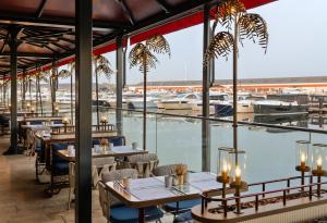 ein Restaurant mit Tischen und Stühlen und einen Yachthafen in der Unterkunft Crowne Plaza - Istanbul Tuzla Viaport Marina, an IHG Hotel in Istanbul