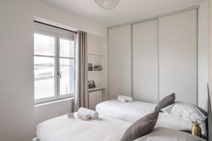 2 camas en una habitación blanca con ventana en L'EUCALYPTUS - Charmant appartement de 52m2 en Dinard