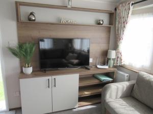 a living room with a flat screen tv on a entertainment center at Chichester Lakeside Self-Catering Holiday Home in Chichester