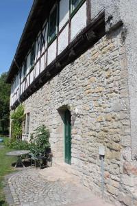 - un bâtiment en pierre avec une porte verte et une table dans l'établissement Ruhige Ferienwohnung im Gutshaus, à Niederorschel