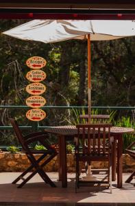 uma mesa com um guarda-sol e uma mesa com cadeiras em Green Village Hotel em Monte Verde
