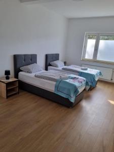two beds in a bedroom with a wooden floor at Twitch Appartments in Achim