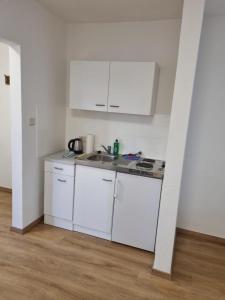 a small kitchen with white cabinets and a sink at Twitch Appartments in Achim