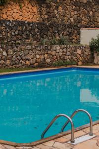a swimming pool with blue water and a stone wall at Green Village Hotel in Monte Verde