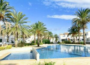 a swimming pool with palm trees and houses at Your House in Menorca in Ciutadella