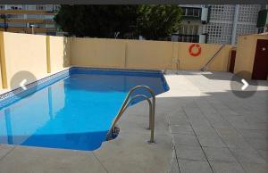 une piscine bleue avec une main courante à côté d'un mur dans l'établissement Ático con vistas cerca del mar - Penthouse - parking - terraza, à Torre del Mar