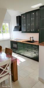 eine Küche mit grünen Schränken und einem Tisch in der Unterkunft Villa Scheckenbach in Sommerach