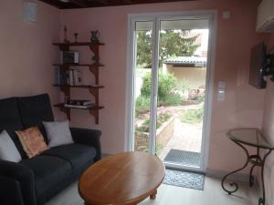 ein Wohnzimmer mit einem Sofa, einem Tisch und einer Glasschiebetür in der Unterkunft L'Escale Dijonnaise in Dijon