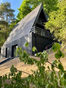 a black barn with a gambrel roof at Domki MODERN Jezioro Nyskie in Nysa