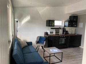 a living room with a blue couch and a kitchen at Feriehus med Sjøutsikt in Sætra