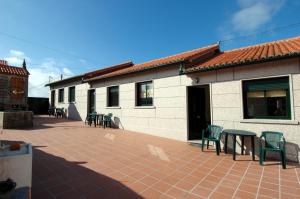 un patio con sillas, una mesa y un edificio en APARTAMENTOS OUTEIRO, en Pobra do Caramiñal