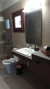 a bathroom with a sink and a toilet and a mirror at Melograno Apartment in Ammouliani