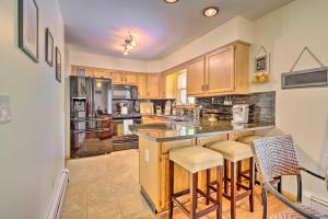a large kitchen with wooden cabinets and a island with bar stools at Cozy Auburn Retreat with Hot Tub - Walk to Lake in Auburn