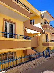 a yellow building with a blue fence in front of it at Edem in Elafonisos