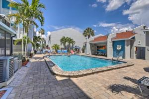 a swimming pool with palm trees next to a building at Poolside Madeira Beach Abode with Balcony! in St Pete Beach