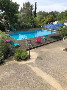una piscina con sillas y sombrillas en un patio en Nîmes calme en Nimes