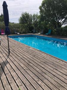una sombrilla en una terraza de madera junto a una piscina en Nîmes calme en Nimes