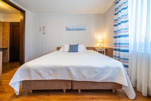um quarto com uma cama grande e lençóis brancos em Pokoje gościnne Angela em Jastarnia