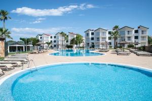 una gran piscina con sillas y apartamentos en condominio en Pierre & Vacances Menorca Cala Blanes en Cala en Blanes