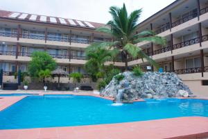 a hotel with a pool and a palm tree in front of it at Best Western Plus Accra Beach Hotel in Teshi