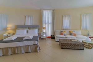 a bedroom with a large bed and a couch at Black Diamond Beachfront Pool Villa Pasithea in Sounio, Athens in Sounio