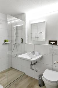 a white bathroom with a sink and a toilet at Apartment nearby Titlis Station in Engelberg
